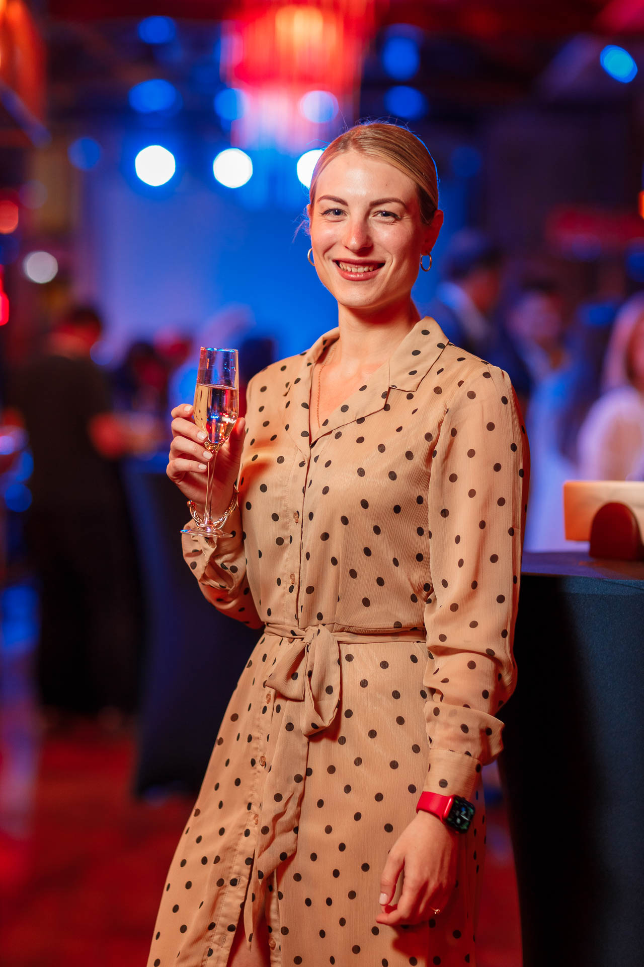 Девушка в платье в горошек с бокалом шампанского в руках на мероприятии
