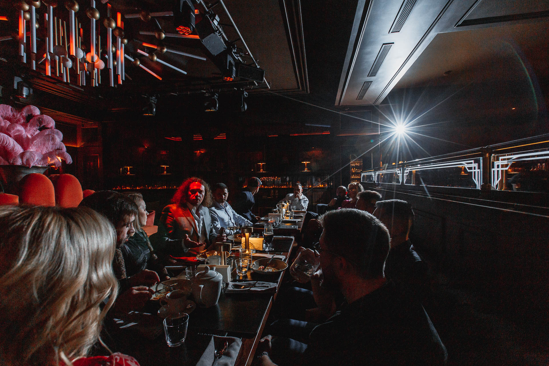 Атмосферная и тускло освещенная модная сцена ресторана, где посетители сидят за столиками, наслаждаясь напитками и беседами
