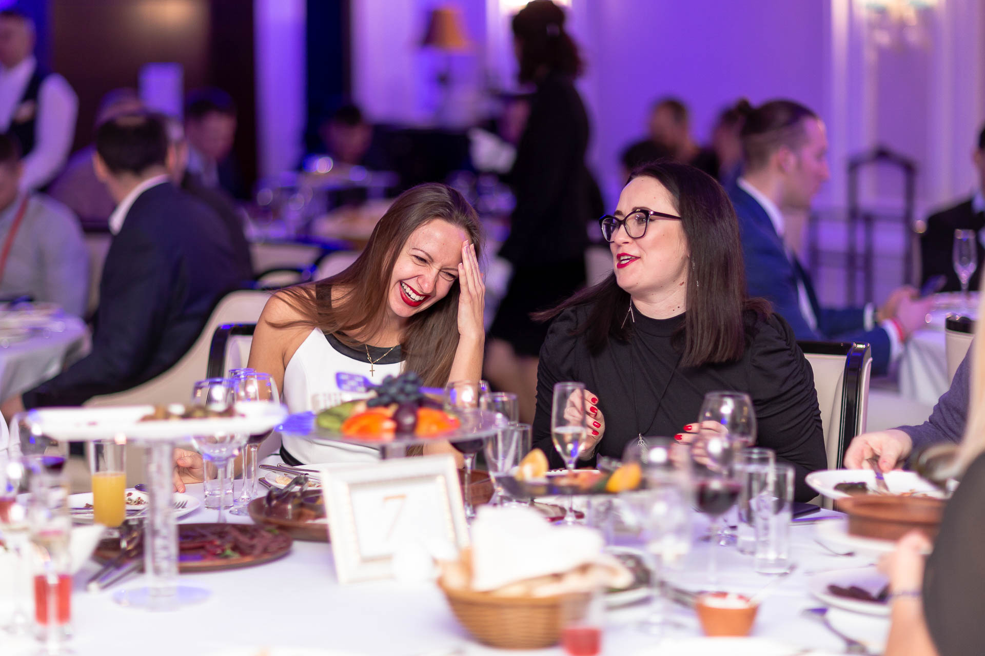 две женщины смеются во время беседы за столом